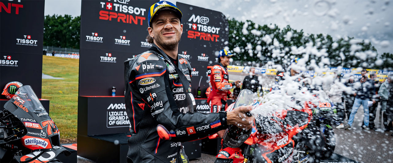 Marco Bezzecchi sprays champagne on the podium after his second-place finish at Sachsenring.