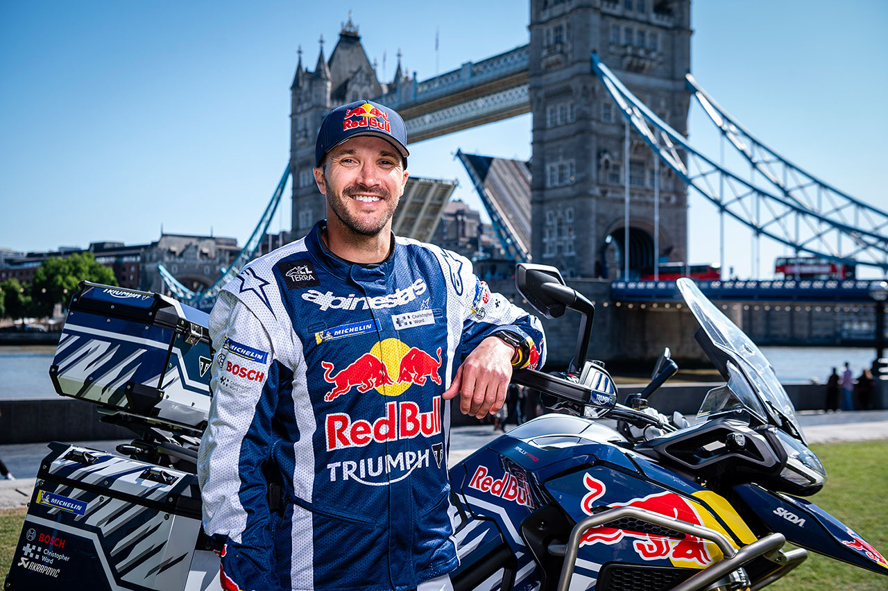Sam Sunderland stands with his Triumph Tiger 1200 Rally Explorer in front of Tower Bridge in London.