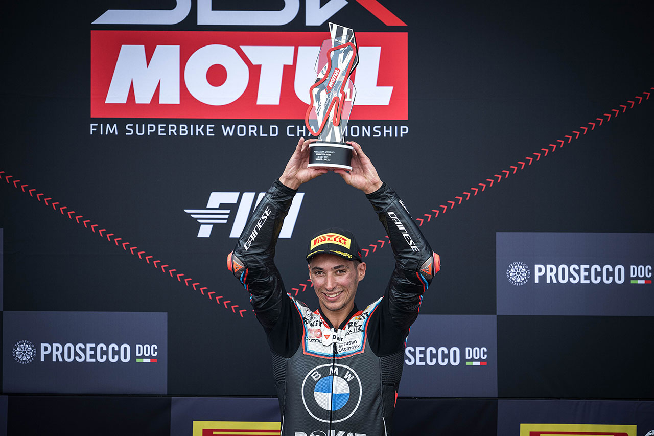Toprak Razgatlioglu holds his trophy on the podium after his triple victory at Donington WorldSBK 2025.